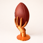 Goldener Football-Ständer in Handform vor hellem Hintergrund